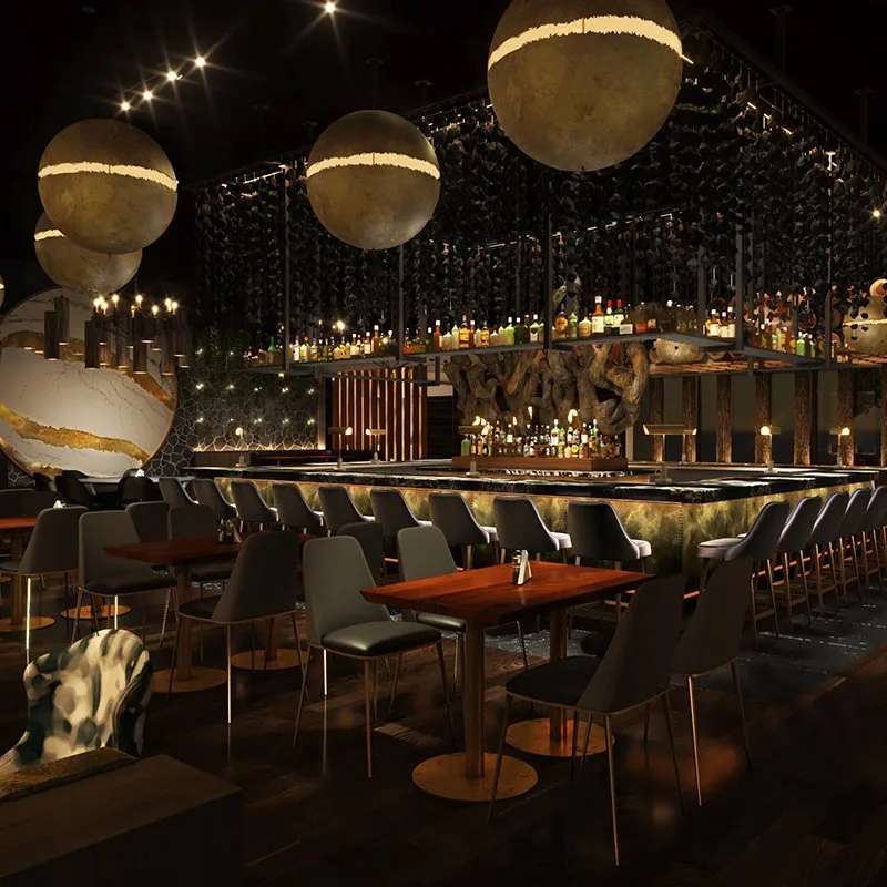 Elegant bar with modern decor, large spherical pendant lights, a marble globe, and a sleek bar counter with various bottles. Seating includes chairs with black upholstery, some patterned, around wooden tables.